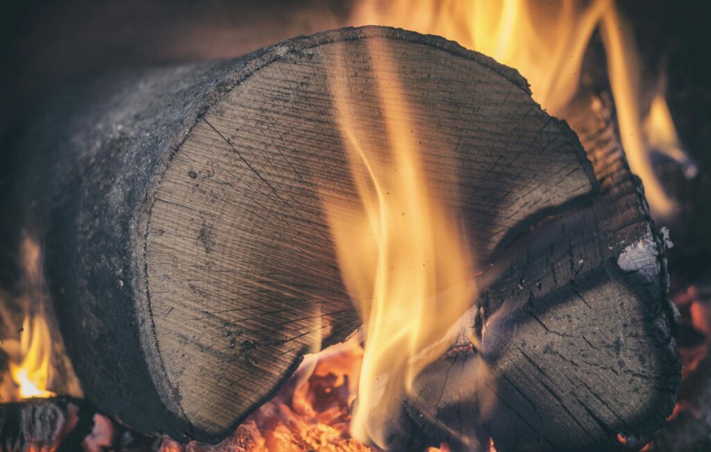 A macro shot of a burning log with visible flames and embers, embodying warmth.